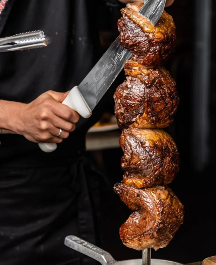 Brazilian barbecue beef on a skewer, carved with a serving knife