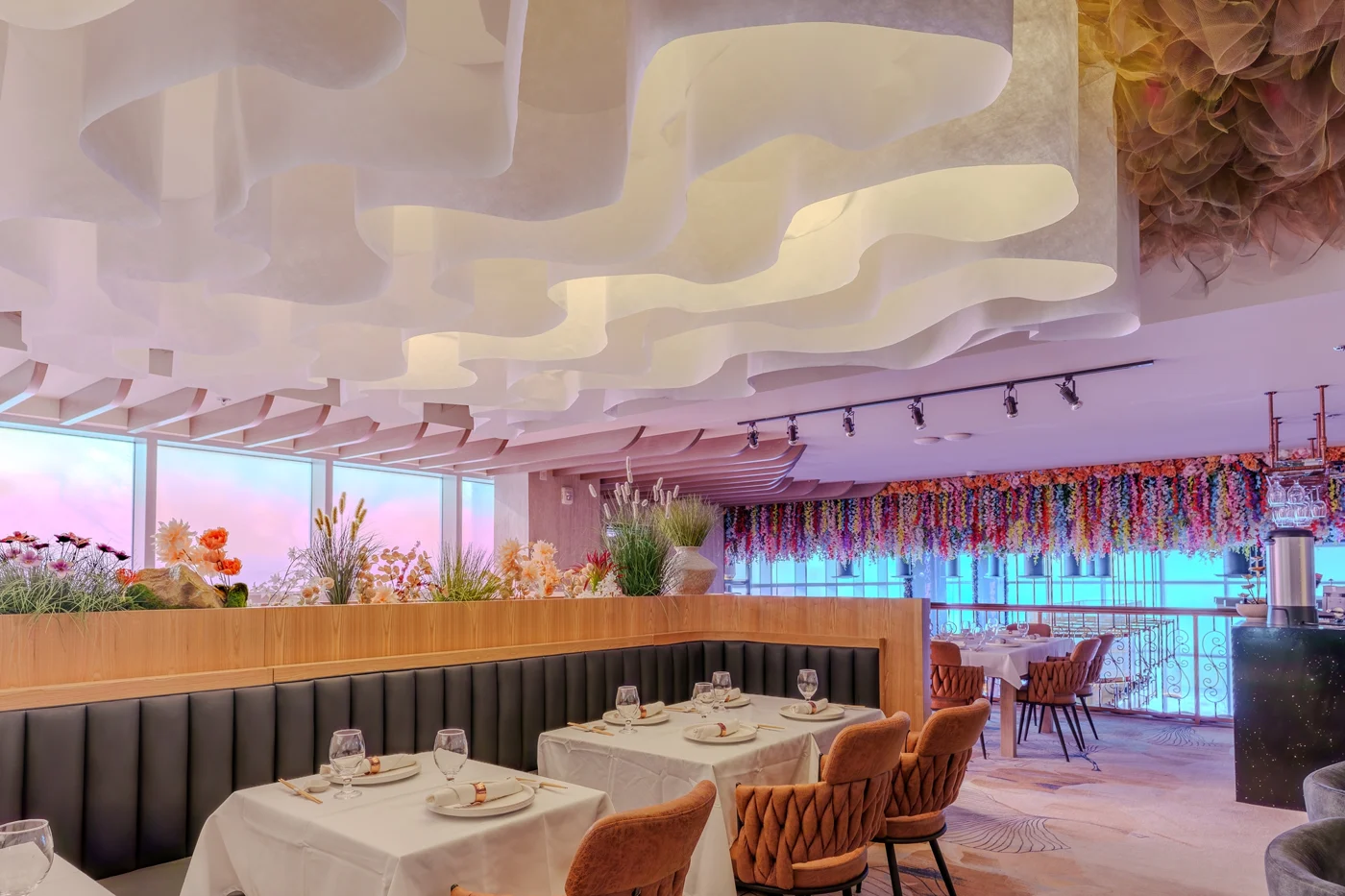Churasuko dining room with sculptural ceiling, warm lighting and dining tables
